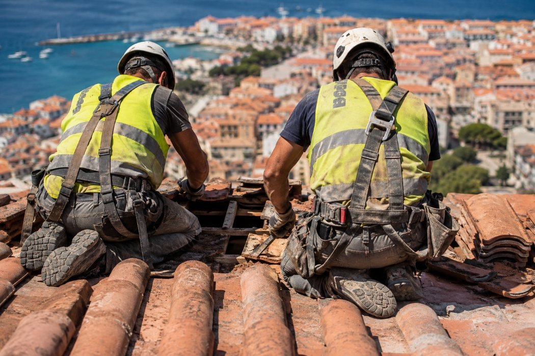 Dos operarios con arnés trabajando sobre una cubierta de teja